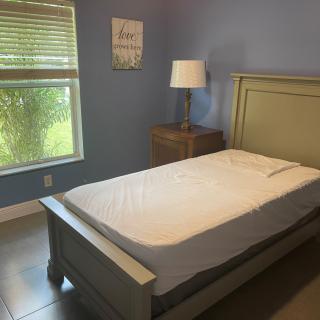 A cozy bedroom with a single bed and a lamp on the nightstand by the window.
