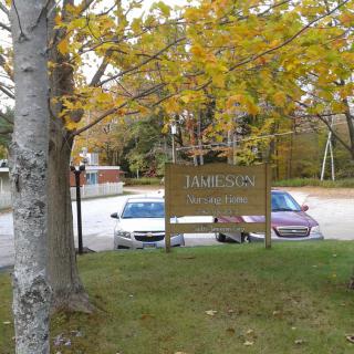 A parking lot with a sign reading 'JAMIESON PARK' surrounded by autumn trees.