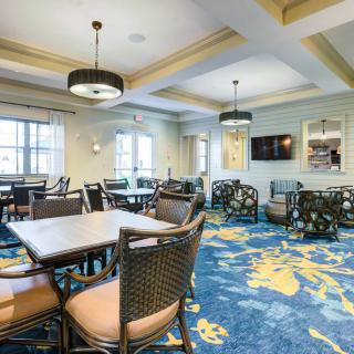 A well-furnished dining room with contemporary decor, featuring tables and chairs on a vibrant blue carpet, illuminated by ceiling lights.