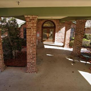 A covered entrance featuring brick columns and a walkway leading to a doorway.