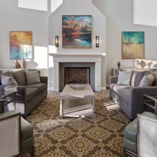 A modern living room with elegant sofas and a fireplace, featuring contemporary artwork and decor.