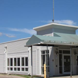A modern public building with a sloped roof and large windows under a clear blue sky.