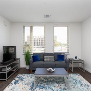 A modern living room with a cozy sofa, patterned carpet, and a television set.