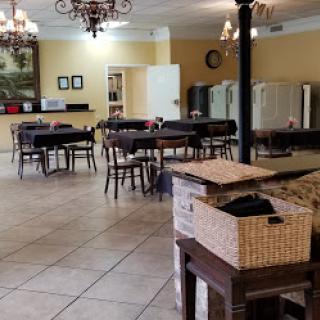 A spacious dining area featuring neatly arranged tables and chairs, complemented by elegant chandeliers.