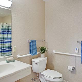 A clean and simple bathroom with essential amenities including a sink, toilet, and grab bars.
