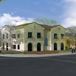 A Mediterranean-style two-story building situated on a corner lot, with several arched windows and surrounded by trees.