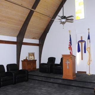 A view of a church sanctuary featuring a wooden pulpit, seating area, and religious symbols.