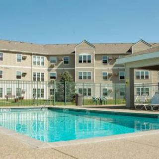 A serene view of an apartment complex featuring a sparkling pool on a sunny day.