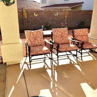 A cozy patio setup with three inviting chairs basking in the sunlight.