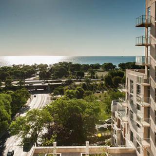 A sunny coastal view with buildings, trees, and a road leading to the ocean.