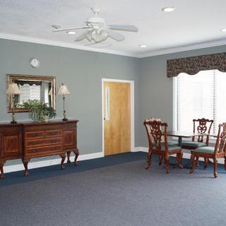 A classic dining room with a sideboard, table, and chairs, adorned by a mirror and window with curtains.