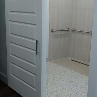 An open door revealing an accessible shower area with grab bars.