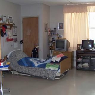 A small hospital room with a bed, television, and medical equipment.