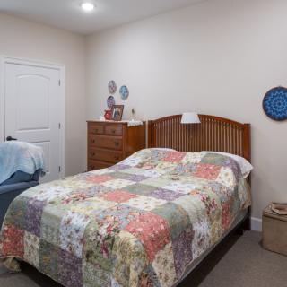 A cozy bedroom featuring a quilt-covered bed and wooden furniture.