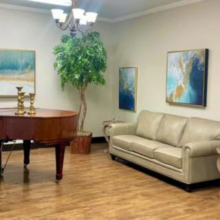 A cozy living room with a grand piano, leather sofa, and elegant artwork.