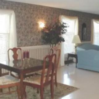 A cozy dining and living area featuring a wooden dining table with chairs, a plush sofa, and large windows allowing natural light to fill the space.