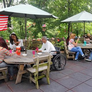 People enjoying a meal outdoors under umbrellas on a restaurant patio.