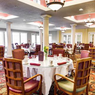 An elegant dining room with neatly arranged tables and chairs, featuring stylish decor and chandeliers.