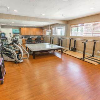 A spacious home gym equipped with various exercise machines and a large table for multi-purpose use.