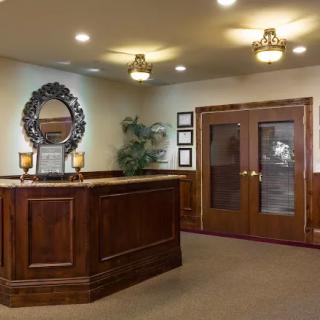 A reception area with wooden furniture and decorative elements, featuring a mirror and elegant lighting.