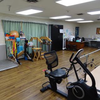 A well-equipped rehabilitation center featuring exercise equipment and a spacious indoor area.