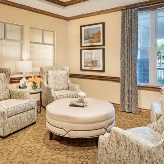A cozy living room with patterned armchairs, a round coffee table, and framed artwork on the walls.