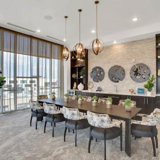 A modern dining room with a large table, decorative wall art, and floor-to-ceiling windows.