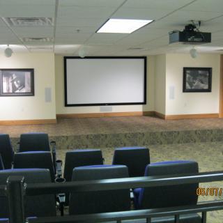 An empty auditorium with a large screen and rows of seats, ready for a presentation.