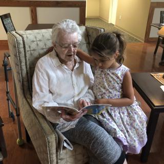 An elderly woman and a young girl reading together in a cozy room.