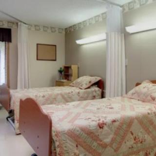 A hospital room with two neatly made beds separated by curtains.