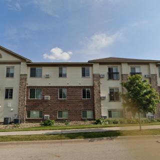 A three-story residential apartment building under a clear blue sky.