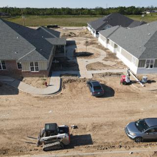 An aerial view of a residential construction site showing new homes and ongoing landscaping work.