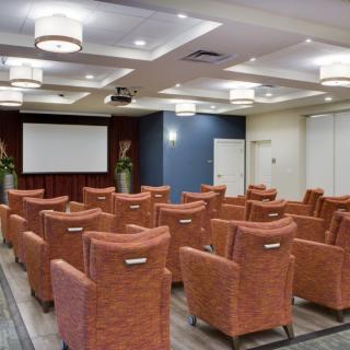 A modern theater-style conference room with comfortable seating and a large projection screen.
