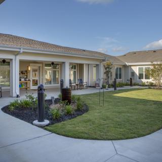 A well-maintained courtyard with a lawn and patio next to a modern building.