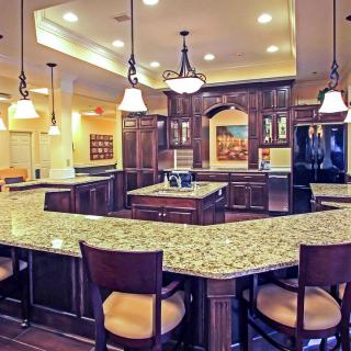 Spacious kitchen with granite countertops and elegant wood cabinets, featuring pendant lighting and bar stools.