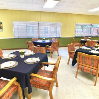 A neatly arranged dining room with tables set for a meal, featuring yellow walls and elegant decor.