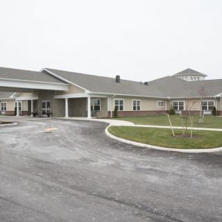 A view of a commercial building with a driveway and landscaped surroundings.