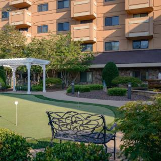 A hotel garden featuring a putting green, with ornate benches and well-maintained landscaping.