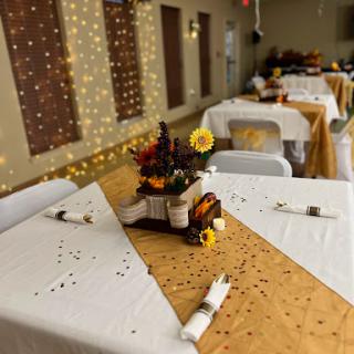 A beautifully arranged table setting featuring autumn-themed decorations and a centerpiece of flowers, perfect for an event or celebration.