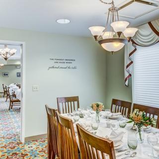 A well-decorated dining room with a set table and elegant chandelier lighting.