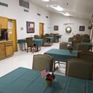 An empty dining area with tables covered in green tablecloths and chairs neatly arranged.