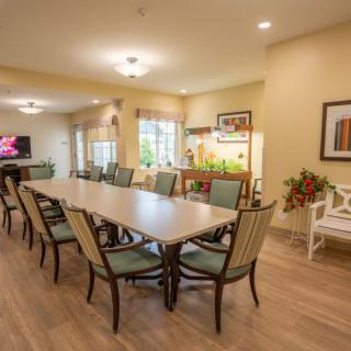 A spacious and well-lit dining area with a long table surrounded by chairs, featuring modern decor and artwork on the walls.