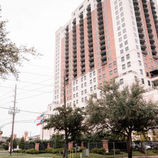 A high-rise apartment building surrounded by trees in an urban setting.