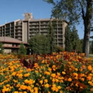 A hotel building surrounded by a colorful garden of flowers and greenery.