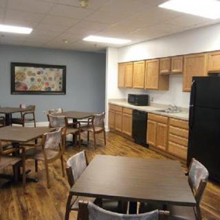 A spacious kitchen and dining area equipped with wooden tables, chairs, and various appliances.