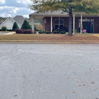 A suburban house with a tree in front and a cloudy sky above.
