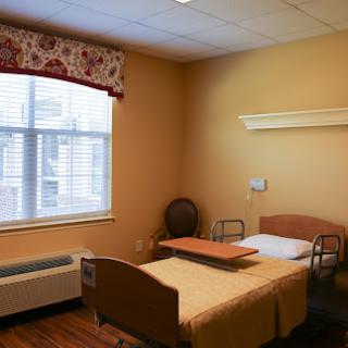 A comfortable and well-lit hospital room featuring a bed, window, and essential furnishings.