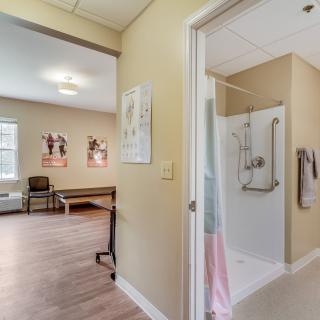 A rehabilitation therapy room with exercise equipment and a shower area.