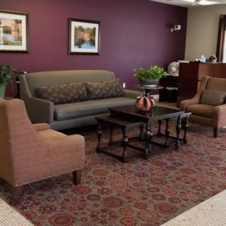 A cozy living room with a sofa, chairs, a coffee table, and decorative elements like framed art and indoor plants.