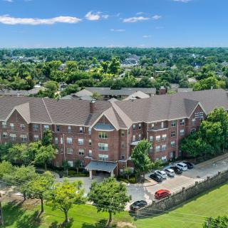 Aerial view of a large residential building surrounded by greenery and a parking lot.